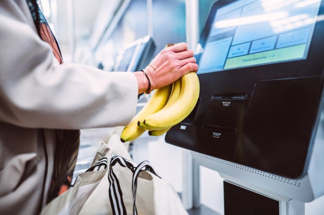 A woman scanning a bunch of bananas at the self checkout in supermarket