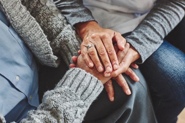 Female carer holding hands of senior man