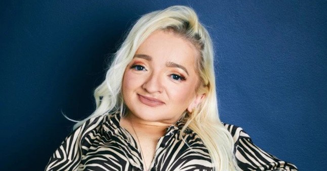 Samantha Renke smiling and wearing a zebra print top, with long blonde hair, against a dark blue background