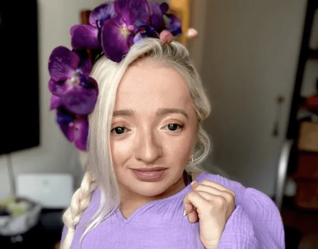 Sam is wearing a purple top and purple flowers in her hair