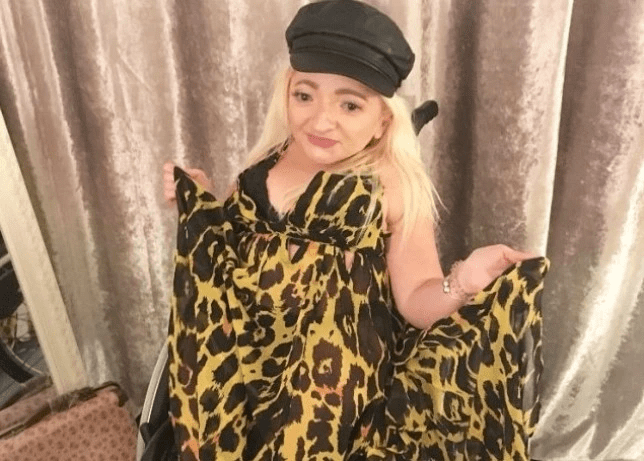 Samantha wearing a leopard print dress and leather cap, in her wheelchair