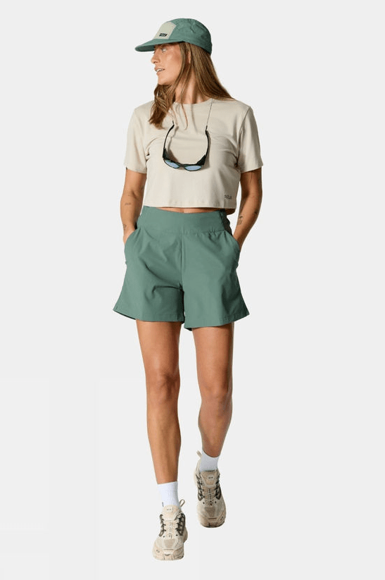 Female wears beige tshirt with green shorts, trainers and matching green hat