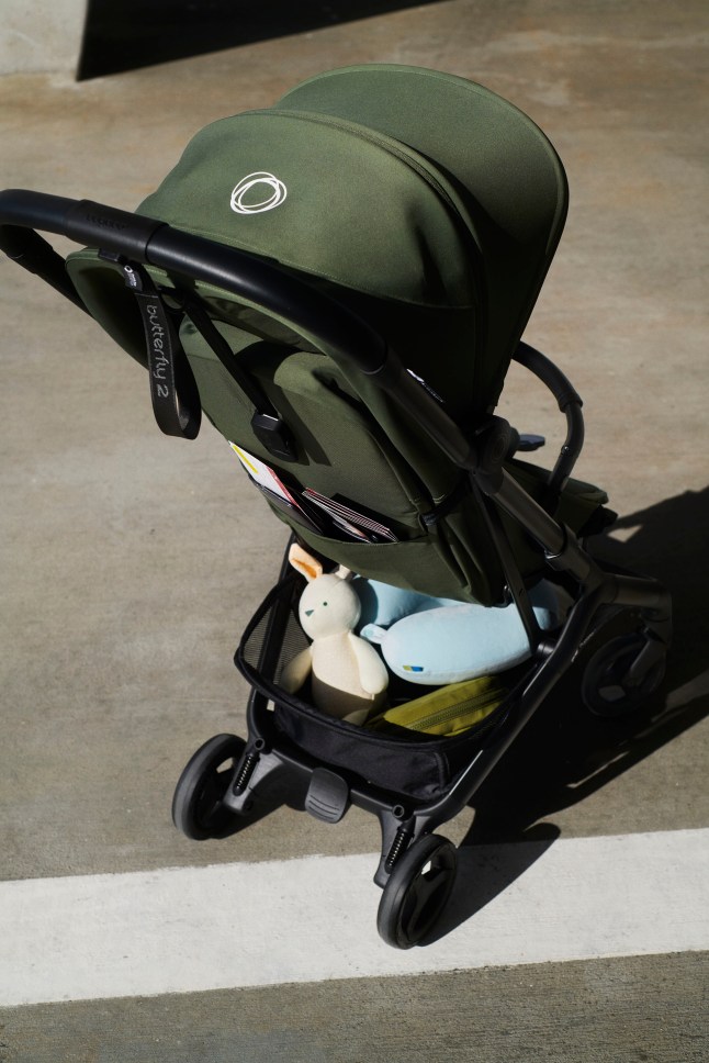 Back of green pushchair with items at the bottom