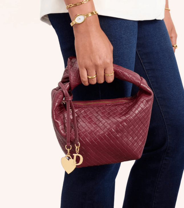 Female holds Abbott Lyon Vienna Mini Leather Bag in Burgundy