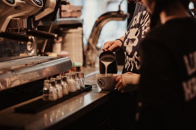 Person making coffee in front of a large silver machine