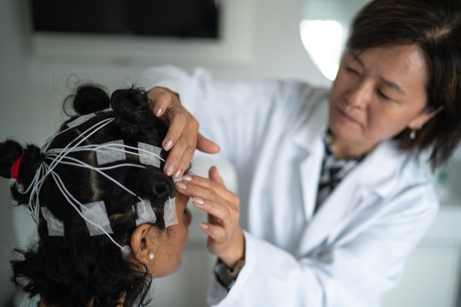 Doctor placing electrodes on patient's head for a polysomnography (sleep study)