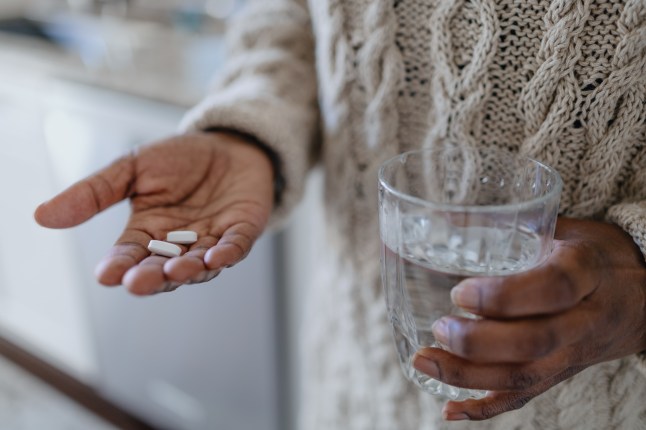 Woman Holds Pills and Glass of Water