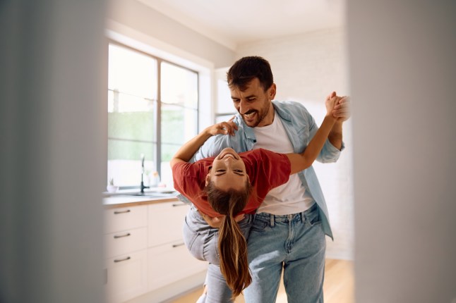 Young happy couple dancing while having fun at home.