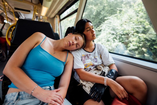 Young women backpackers sleeping on train