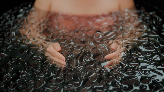 Young Asian woman playing with ice cubes while having an ice bath therapy.