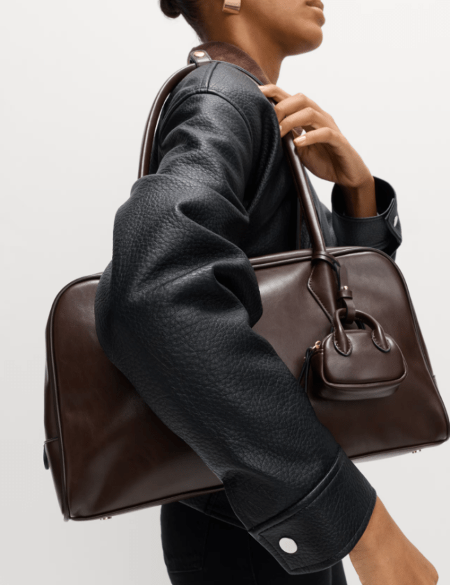 Female holds M&S Faux Leather Bowler Bag