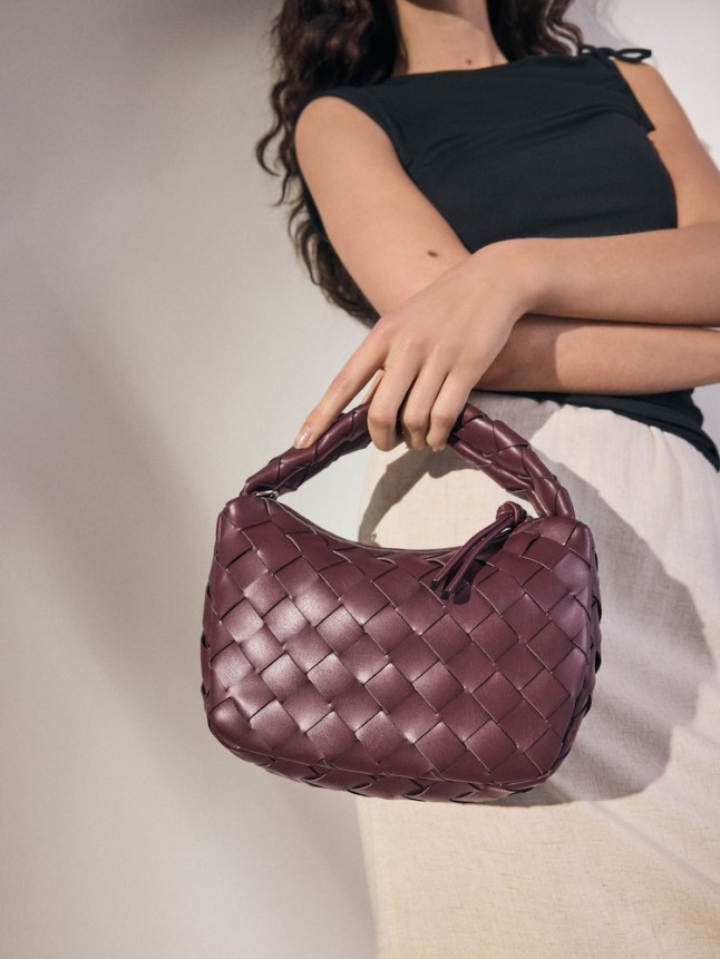 Female holds burgundy Next bag