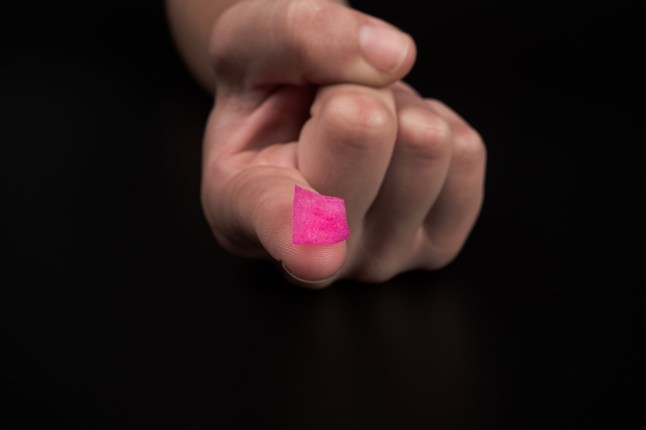 pink lsd stamp mark on fingertip, recreational drugs lysergic acid intake.