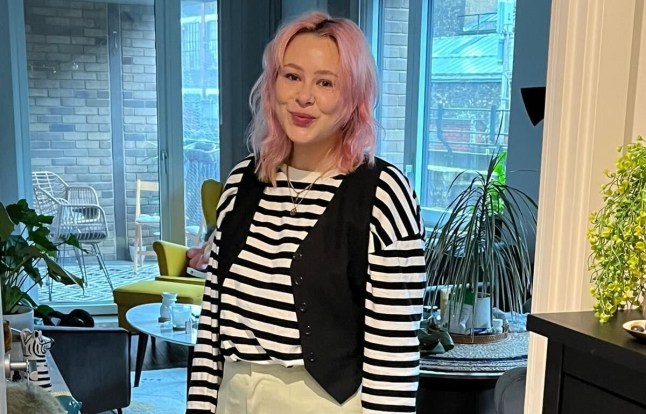 Jessica Lindsay in a black and white striped top smiling at the camera in her house