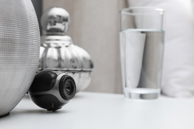 Small hidden camera on white nightstand in bedroom