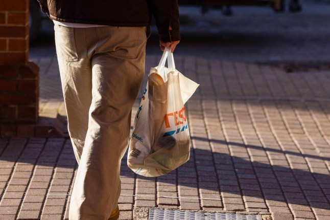 A shopper carrying a Tesco bag for life outside on the street