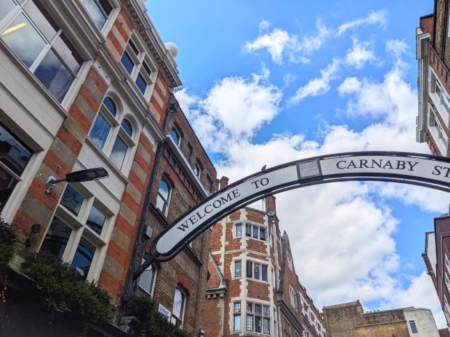 Iconic 'Welcome to Carnaby Street' arch against traditional London architecture and a blue sky