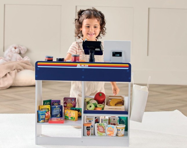 A little girl playing with a wooden Aldi till