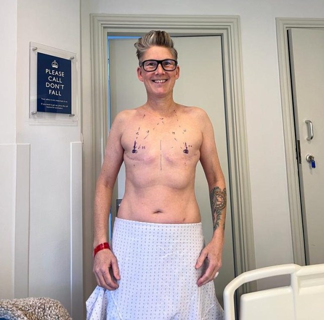 Kit smiling while showing their flat chest, post surgery