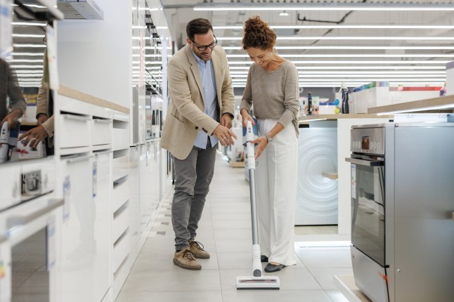 A married couple exploring new vacuum cleaner options at the electronics store