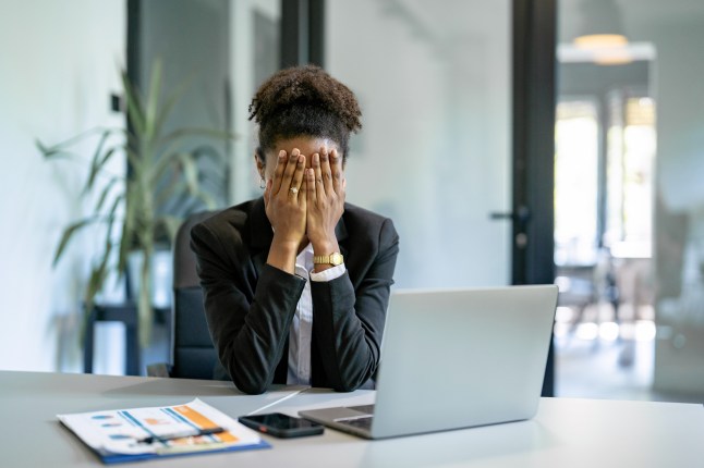 Stressed businesswoman covering her face at work
