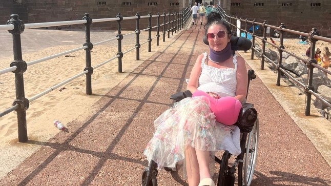 Debbie Whitehouse smiles in her wheelchair on a sunny day out