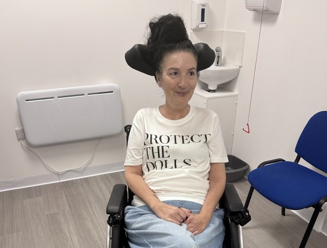 Debbie Whitehouse smiles while wearing a 'protect the dolls' t-shirt