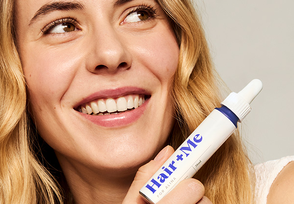 Woman holding the Hair + Me haircare doser