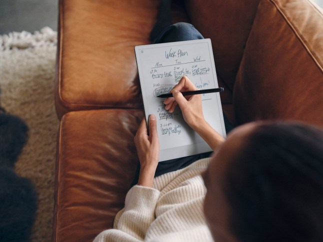 Some holding the reMarkable tablet and writing on it on their lap