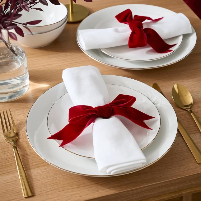 White plates with white napkins and red ribbons tied around