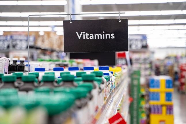 Close up of vitamins aisle sign hanging above supplement shelves