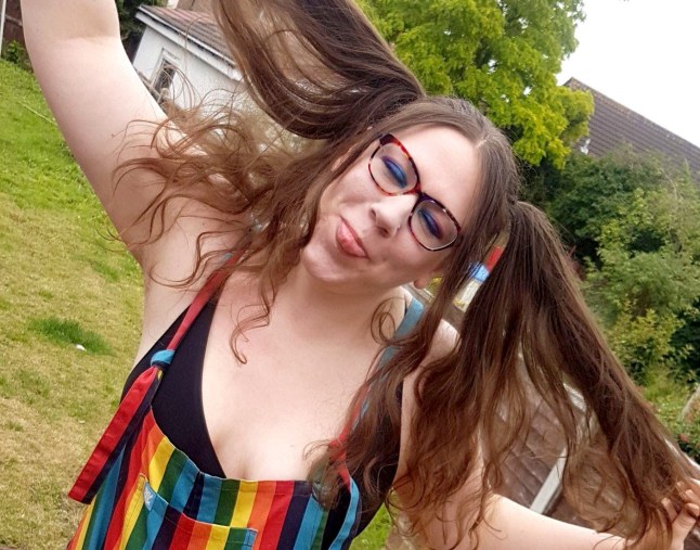 Hannah Shewan Stevens sticks tongue out and wears rainbow dungarees