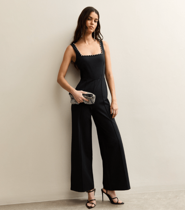 Female wears black jumpsuit with beading around the neckline