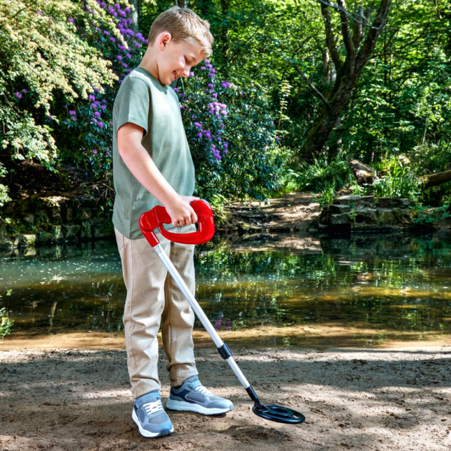 Small boy holding metal detector against the ground