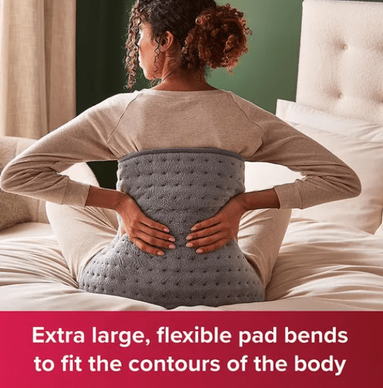 Female holds heated pad against her back.