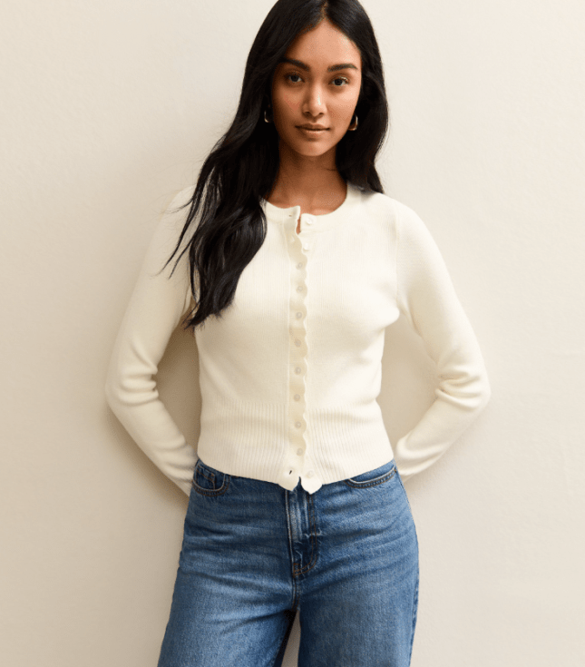 Female wears cream cardigan with blue jeans