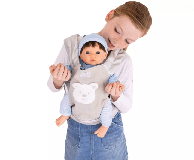 Female child holding doll baby in carrier
