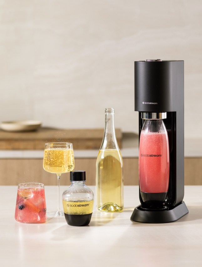 Drinks maker with bottle filled with pink loquid, in a kitchen setting