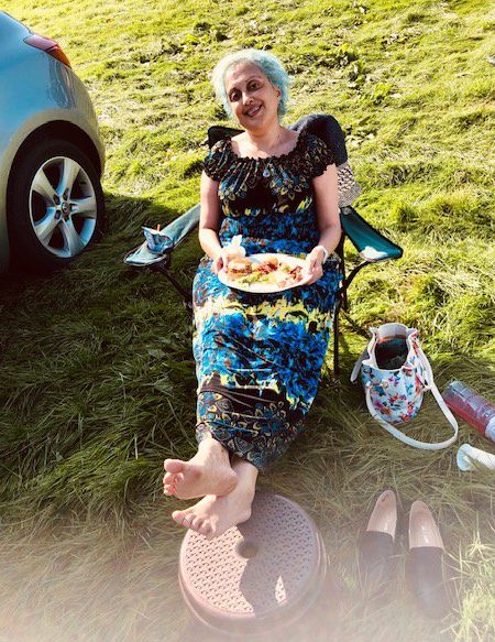 Sufia Taylor sits on a camping chair with a plate of food in her lap.
