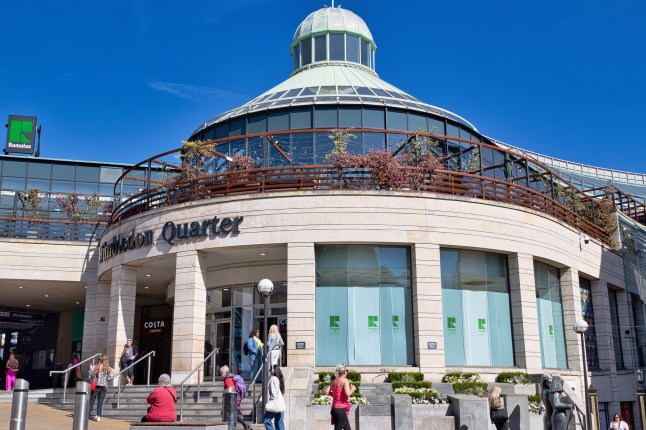 London, UK - 03152025: Exterior view of Wimbledon Quarter shopping centre on a sunny day. People are entering and exiting the building. Clear blue sky overhead.; Shutterstock ID 2627103455; purchase_order: -; job: -; client: -; other: