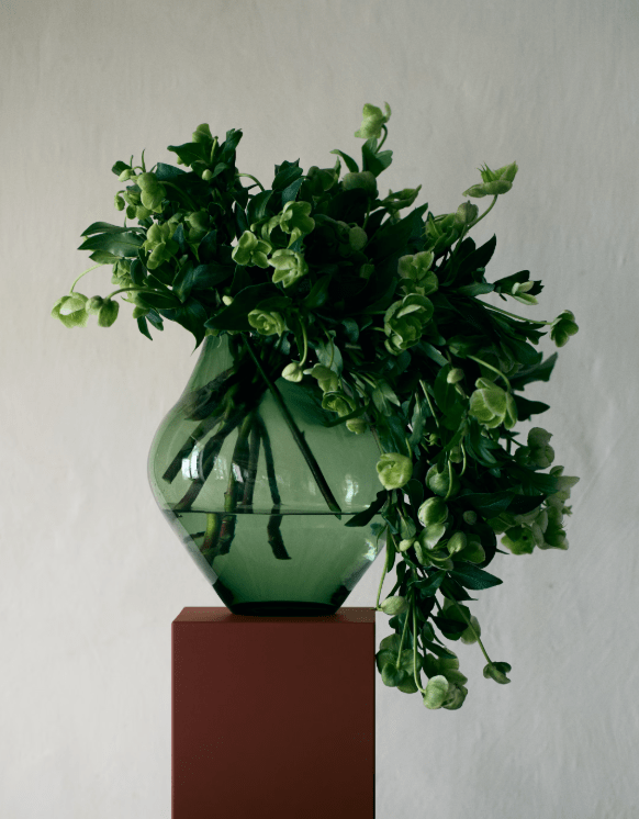 Green vase with green plant, draped over the edge
