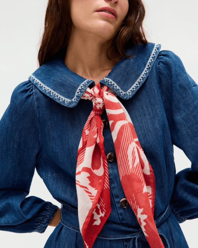 Female wears denim shirt with red and white scarf around her neck