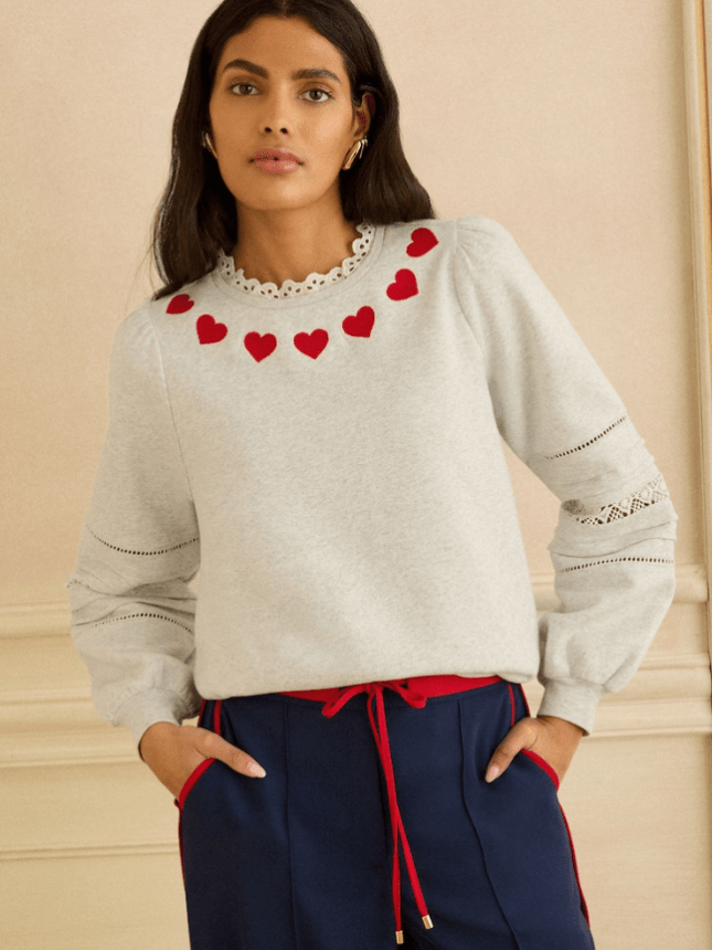 Female wears grey sweater with hearts around the neck