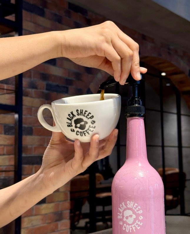 Hands pumping liquid to a branded mug