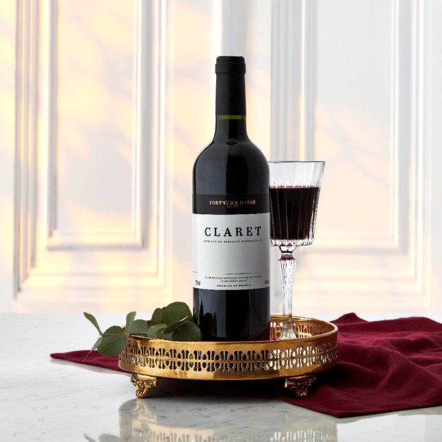 A bottle of Fortnums Claret on a tray, with a glass of wine next to it