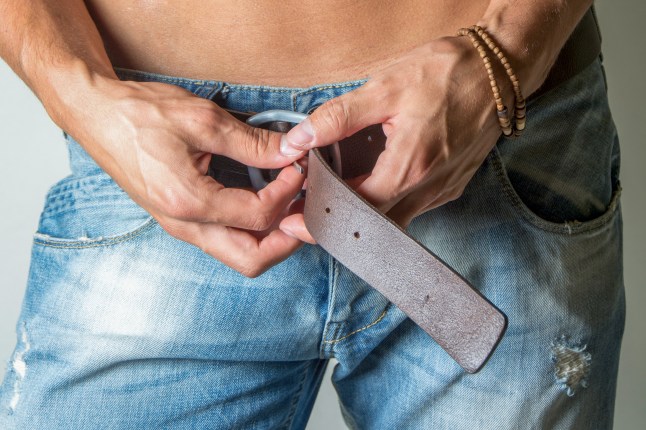 Young handsome man undoing his belt and jeans