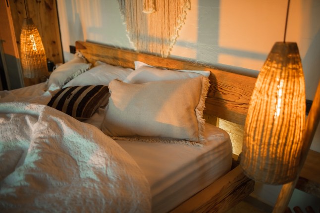 Evening romantic mood in bedroom. Stylish room with handmade design elements in boho style. Beautiful light in Cozy home.