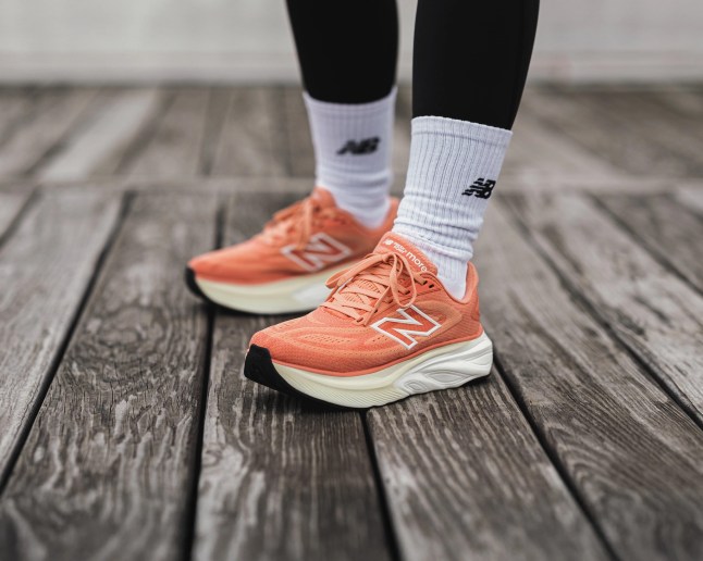 Feet show orange trainers on wooden flooring