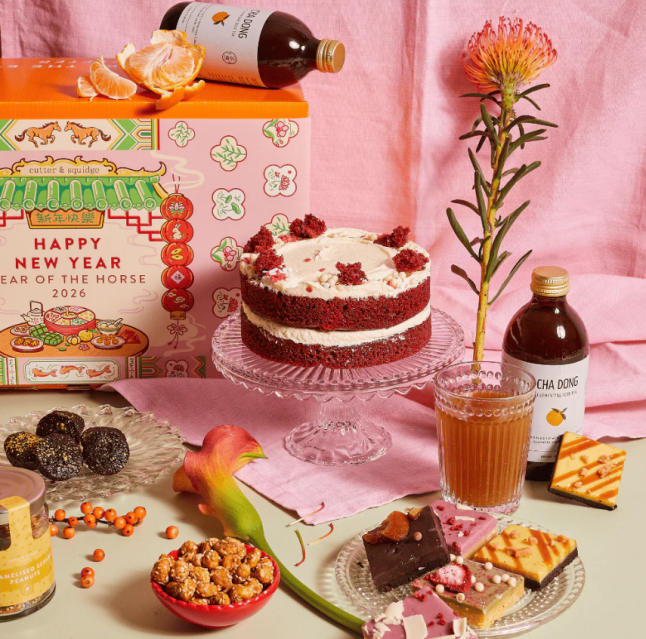 Cake on a stand with treats and tea items surrounding