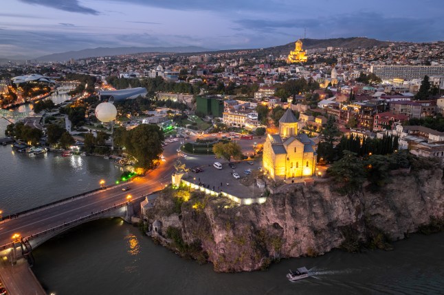 Tbilisi Old Town at dusk: City lights illuminate historic architecture and the Mtkvari River in Georgia